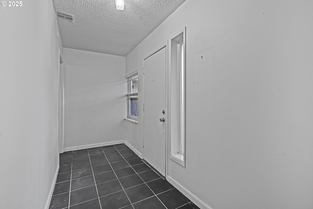 laundry area featuring dark tile patterned floors and a textured ceiling