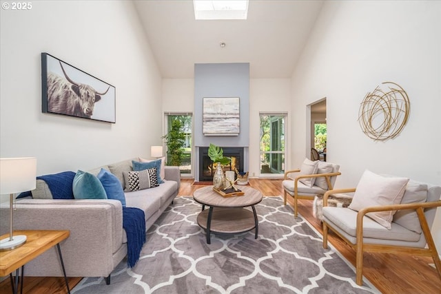12960 SW 5th St, Beaverton, OR 97005 - living area with high vaulted ceiling, healthy amount of natural light, wood finished floors, a lit fireplace, and a skylight