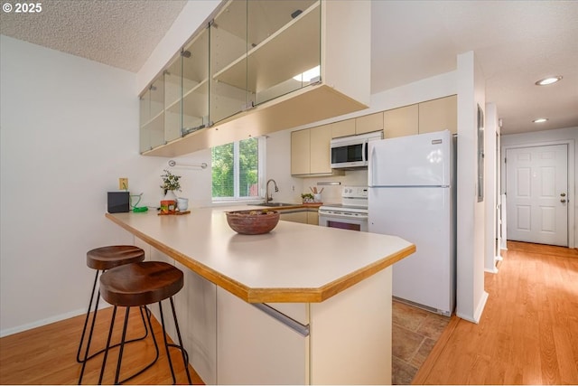 12960 SW 5th St, Beaverton, OR 97005 - kitchen featuring white appliances, a peninsula, a breakfast bar area, light countertops, and recessed lighting