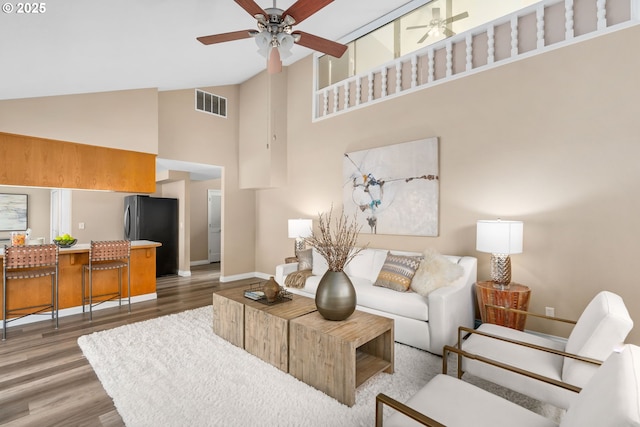 living room with visible vents, baseboards, light wood-style floors, and ceiling fan