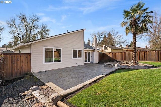 back of property with a yard, a patio, a fenced backyard, and a chimney