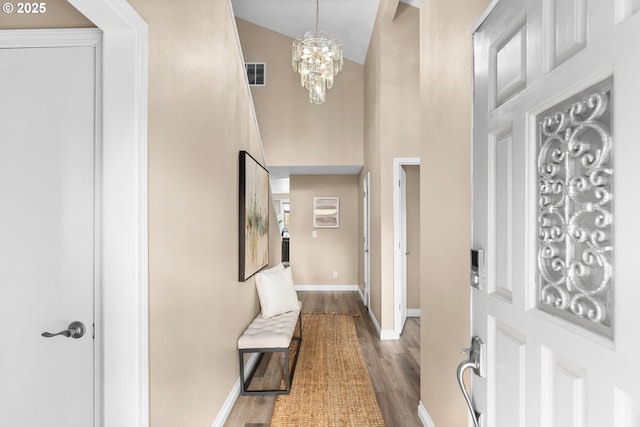 foyer with visible vents, dark wood-type flooring, high vaulted ceiling, a notable chandelier, and baseboards