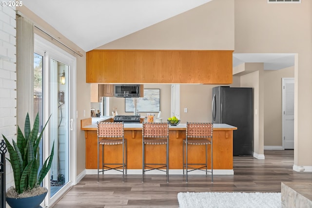 kitchen featuring visible vents, light countertops, lofted ceiling, wood finished floors, and stainless steel appliances