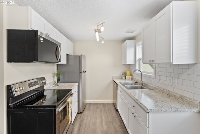 16825 SE Powell Blvd, Portland, OR 97236 - kitchen with appliances with stainless steel finishes, a sink, baseboards, light wood-style floors, and backsplash