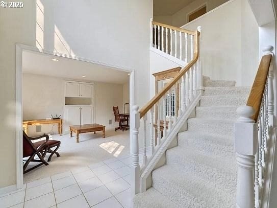 stairway with tile patterned floors and a high ceiling