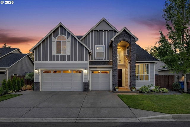 view of front of house featuring board and batten siding, fence, a garage, stone siding, and driveway