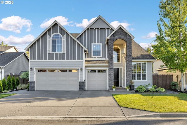 view of front facade featuring fence, an attached garage, concrete driveway, stone siding, and board and batten siding