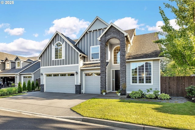 view of front of property with driveway, stone siding, fence, board and batten siding, and a garage