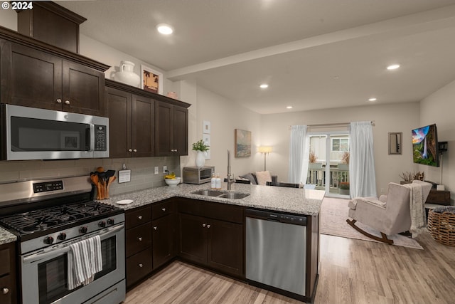 kitchen featuring sink, kitchen peninsula, stainless steel appliances, and light wood-type flooring