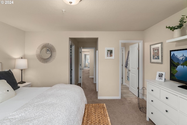 bedroom with light colored carpet and a textured ceiling