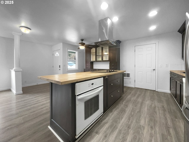 kitchen featuring wood counters, decorative columns, island range hood, ceiling fan, and oven