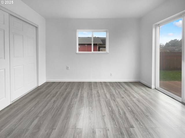 unfurnished bedroom featuring wood-type flooring, a closet, and multiple windows