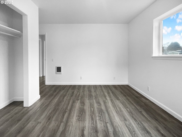 unfurnished bedroom with heating unit and dark wood-type flooring