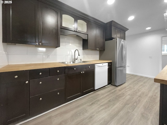 kitchen with stainless steel refrigerator, dishwasher, sink, light hardwood / wood-style flooring, and wooden counters