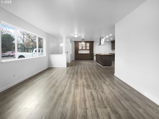 unfurnished living room featuring ceiling fan and dark wood-type flooring