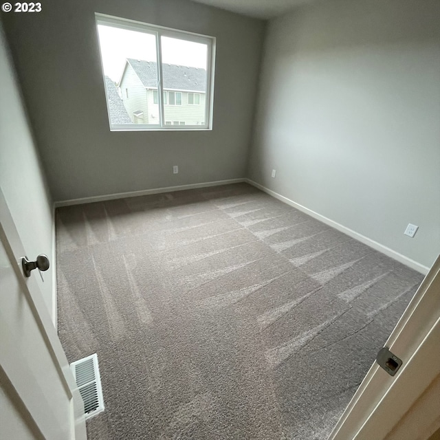 unfurnished room featuring carpet, visible vents, and baseboards