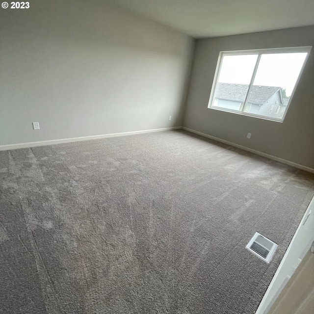 spare room featuring carpet, visible vents, and baseboards