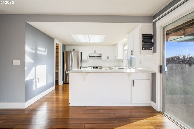 5219 Spring Leaf Ct N, Keizer, OR 97303 - kitchen featuring freestanding refrigerator, under cabinet range hood, a peninsula, and hardwood / wood-style floors