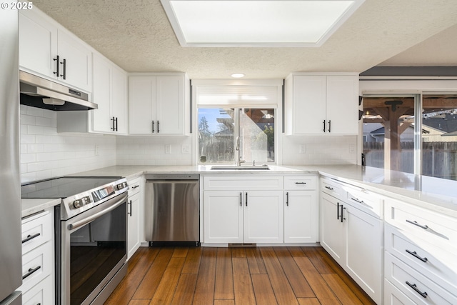 5219 Spring Leaf Ct N, Keizer, OR 97303 - kitchen featuring appliances with stainless steel finishes, under cabinet range hood, white cabinetry, dark wood-style floors, and a textured ceiling