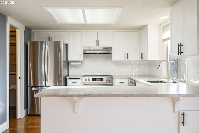 5219 Spring Leaf Ct N, Keizer, OR 97303 - kitchen with appliances with stainless steel finishes, under cabinet range hood, a peninsula, backsplash, and a textured ceiling