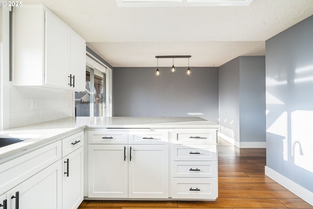 5219 Spring Leaf Ct N, Keizer, OR 97303 - kitchen with a peninsula, wood finished floors, white cabinetry, decorative backsplash, and pendant lighting