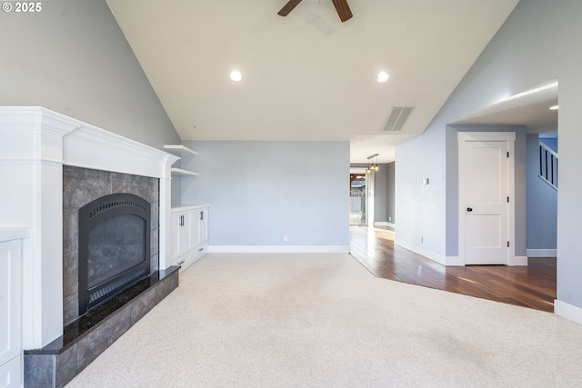 carpeted living room featuring visible vents, baseboards, ceiling fan, and a tile fireplace