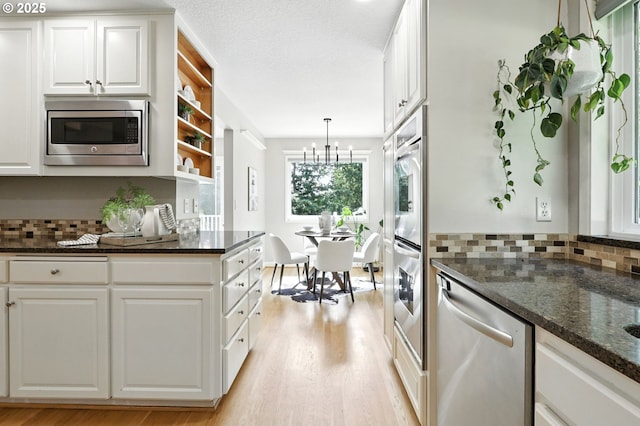 20681 S Wisteria Rd, West Linn, OR 97068 - kitchen featuring appliances with stainless steel finishes, light wood-style flooring, backsplash, a chandelier, and white cabinetry
