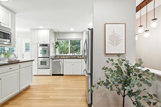 20681 S Wisteria Rd, West Linn, OR 97068 - kitchen featuring appliances with stainless steel finishes, dark countertops, light wood-type flooring, white cabinets, and recessed lighting