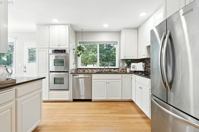 20681 S Wisteria Rd, West Linn, OR 97068 - kitchen with appliances with stainless steel finishes, backsplash, light wood-type flooring, white cabinets, and recessed lighting