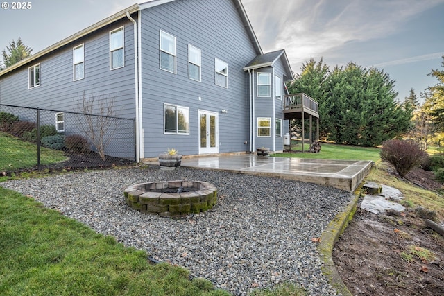 back of property with a patio area, a wooden deck, and a fire pit