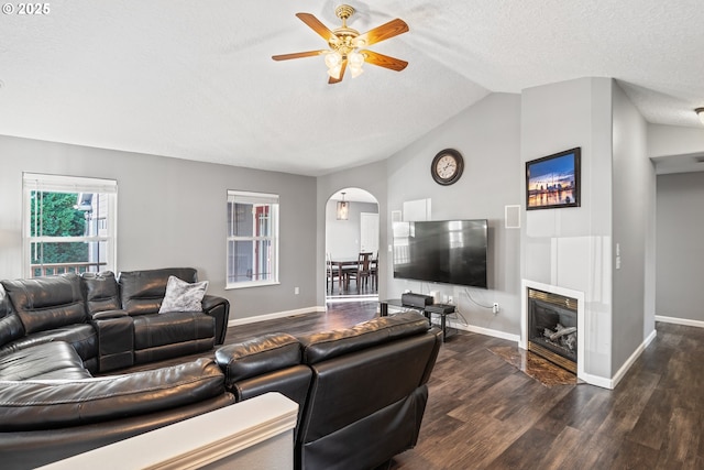 living room with dark wood-type flooring, ceiling fan, lofted ceiling, and a textured ceiling