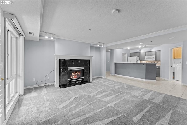 15420 NE Knott St Unit 2, Portland, OR 97230 - unfurnished living room featuring baseboards, washer / clothes dryer, light colored carpet, a textured ceiling, and track lighting