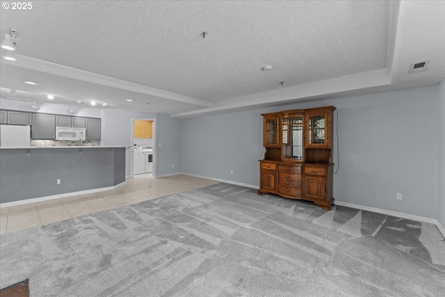 15420 NE Knott St Unit 2, Portland, OR 97230 - unfurnished living room featuring a tray ceiling, a textured ceiling, crown molding, baseboards, and washer and dryer