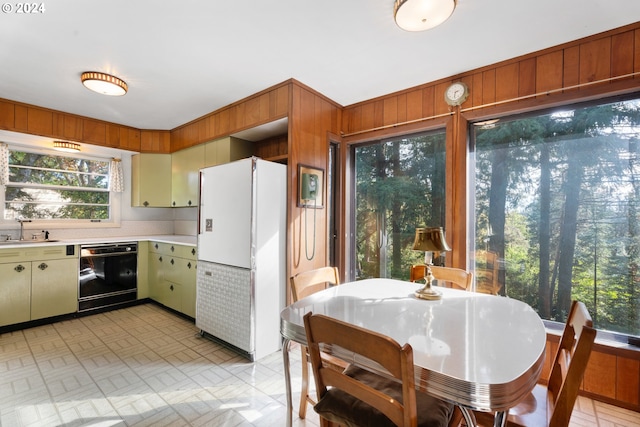 6455 SW Scholls Ferry Rd, Portland, OR 97223 - kitchen with black dishwasher, freestanding refrigerator, light countertops, and wood walls