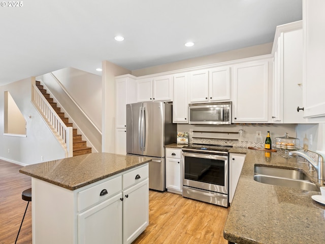 13143 SW Brianne Way, Portland, OR 97223 - kitchen featuring stainless steel appliances, light wood finished floors, white cabinets, a center island, and recessed lighting