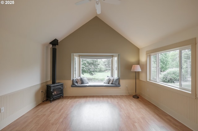 living room with wood finished floors, a wood stove, lofted ceiling, and a ceiling fan