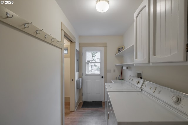 clothes washing area with cabinet space, washing machine and clothes dryer, and light wood-type flooring