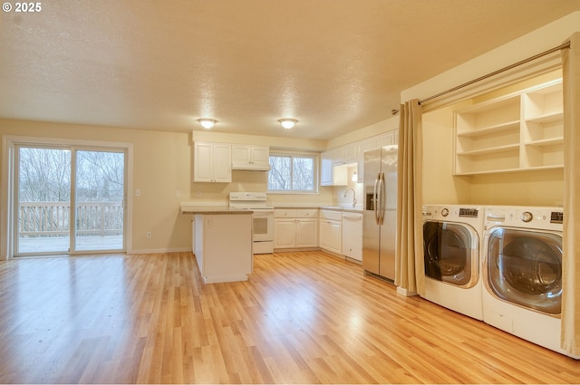 laundry area featuring a wealth of natural light, light hardwood / wood-style flooring, washing machine and clothes dryer, and sink