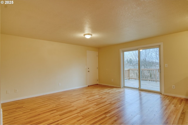 unfurnished room with light wood-type flooring and a textured ceiling