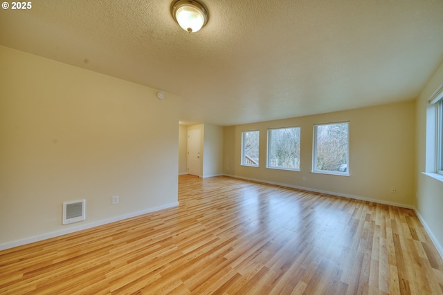 empty room featuring a textured ceiling and light hardwood / wood-style flooring