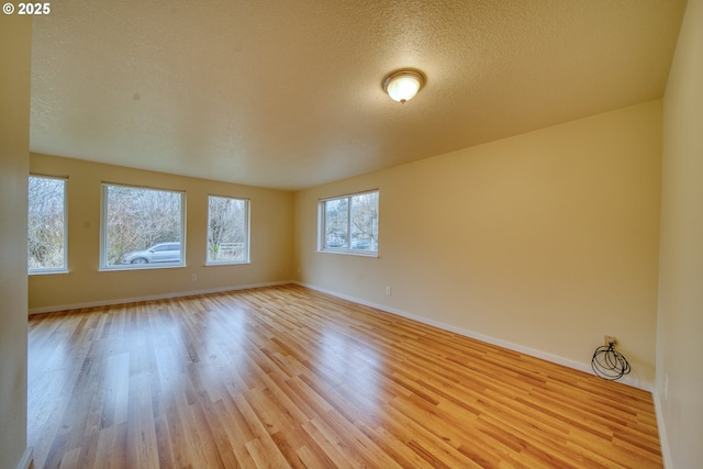 spare room with light wood-type flooring and a textured ceiling