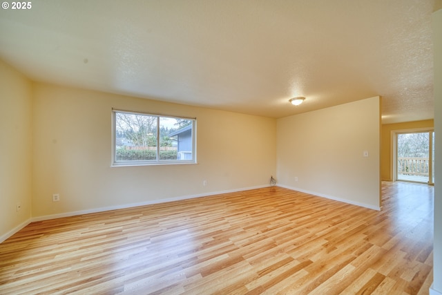 spare room featuring a textured ceiling and light hardwood / wood-style flooring