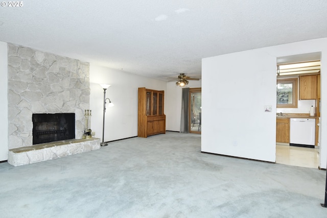 unfurnished living room featuring light colored carpet, ceiling fan, a fireplace, and a textured ceiling