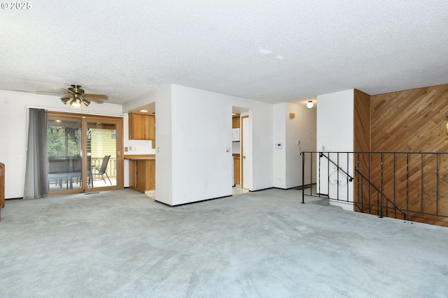 spare room with light colored carpet, wood walls, and a textured ceiling