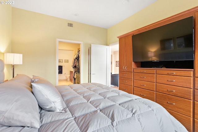 bedroom with ensuite bath, a spacious closet, and a closet