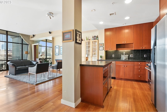 kitchen featuring stainless steel refrigerator, light hardwood / wood-style flooring, and backsplash