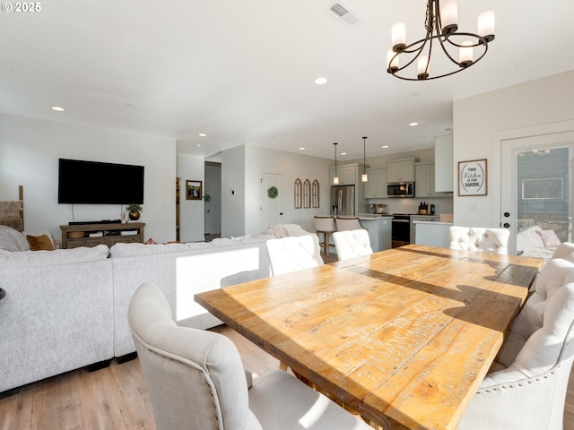 dining space with an inviting chandelier and light hardwood / wood-style flooring