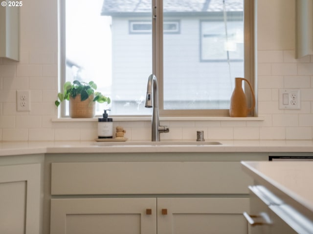 interior space featuring tasteful backsplash, sink, and white cabinetry