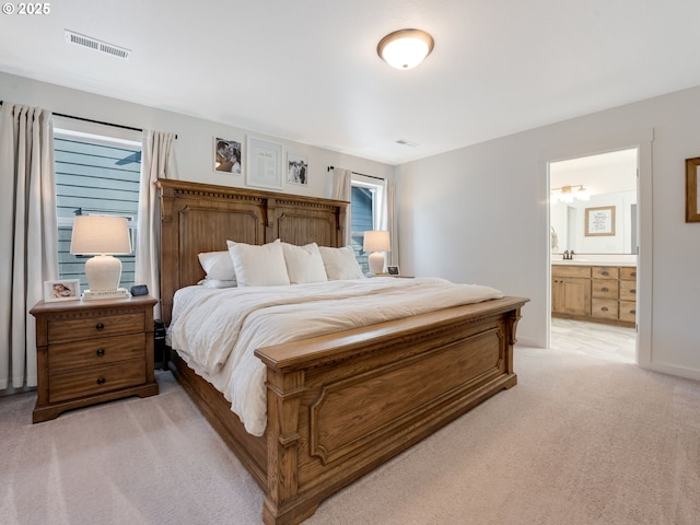 bedroom featuring connected bathroom and light colored carpet