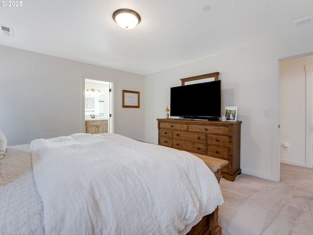 bedroom featuring ensuite bath and light colored carpet